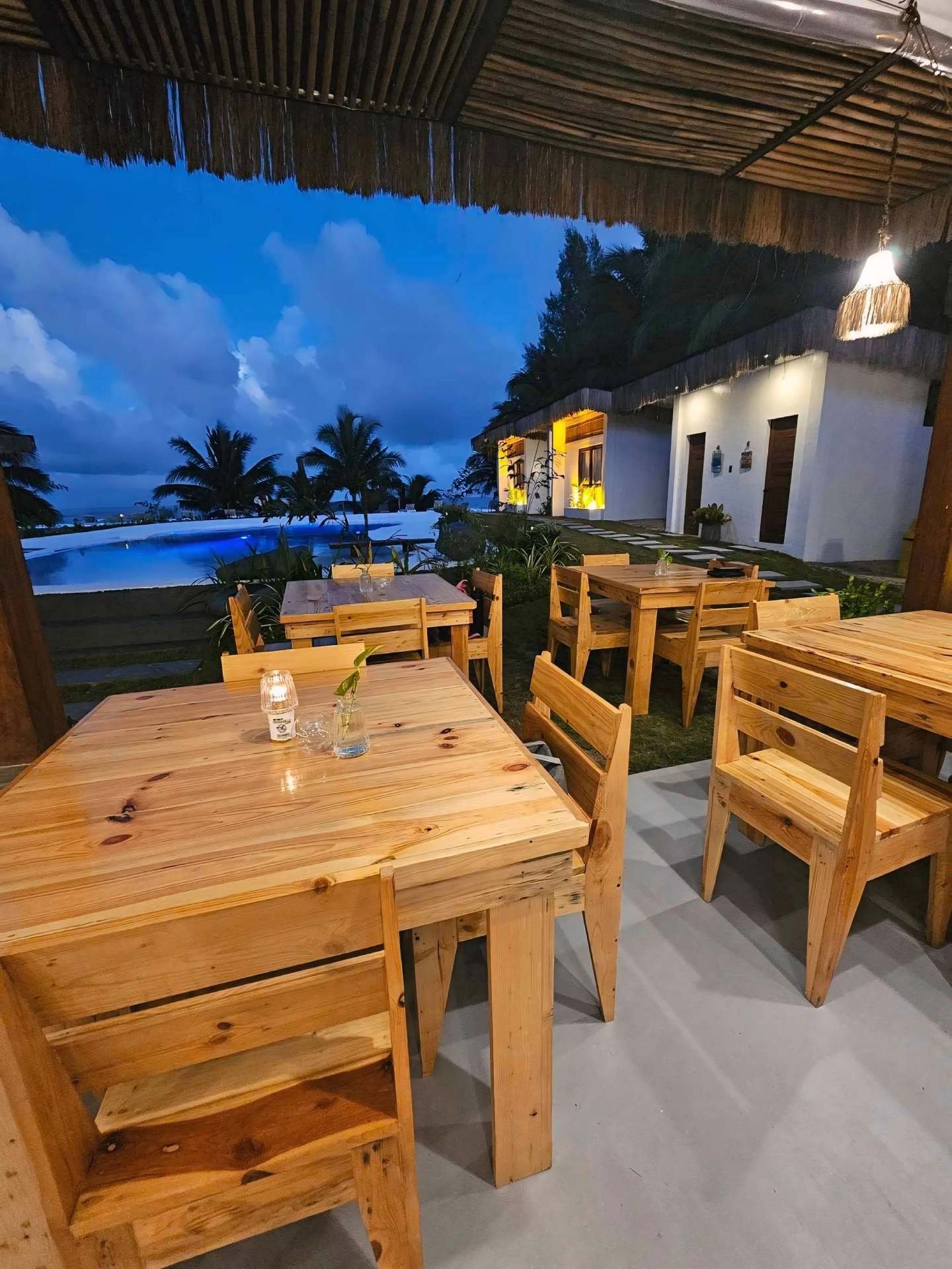 Outdoor dining tables at Sun and Waves Resort with pool and ocean view