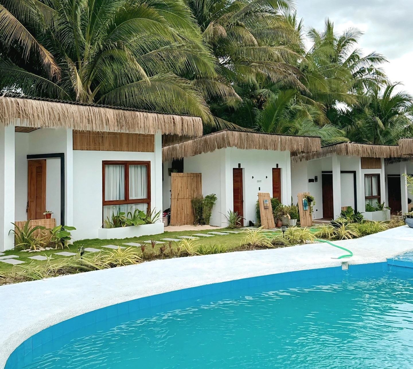 Sun and Waves Resort bungalows by the pool with coconut trees