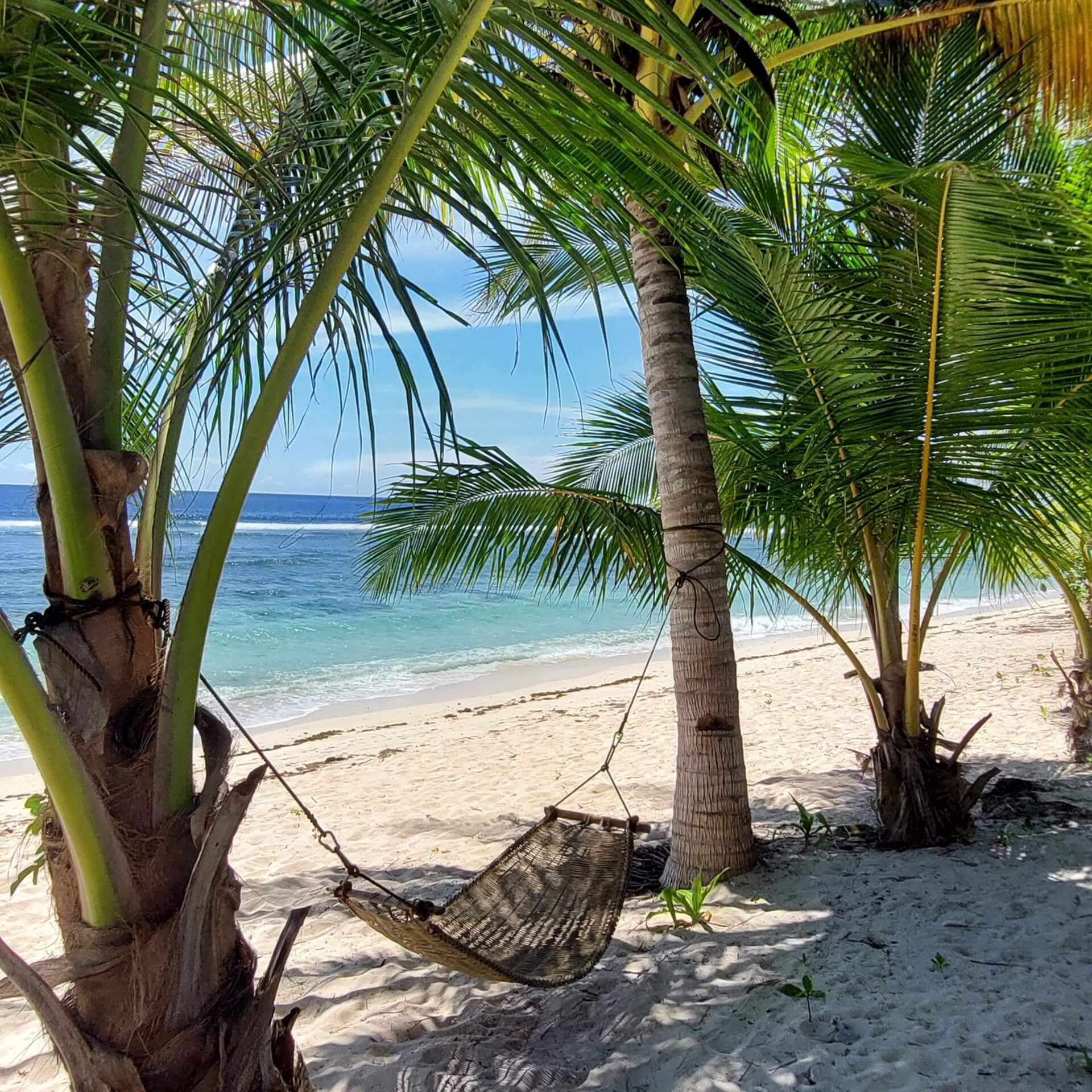 Hammock between palm trees on a sandy beach in Baganga, Davao Oriental, Philippines